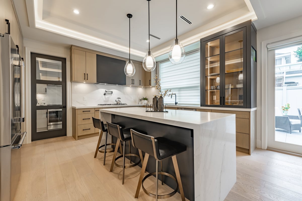 Kitchen interior with bar stools white countertops wooden cabinets pendant lighting extra kitchen sink glass cabinets hardwood floors stainless steel appliances