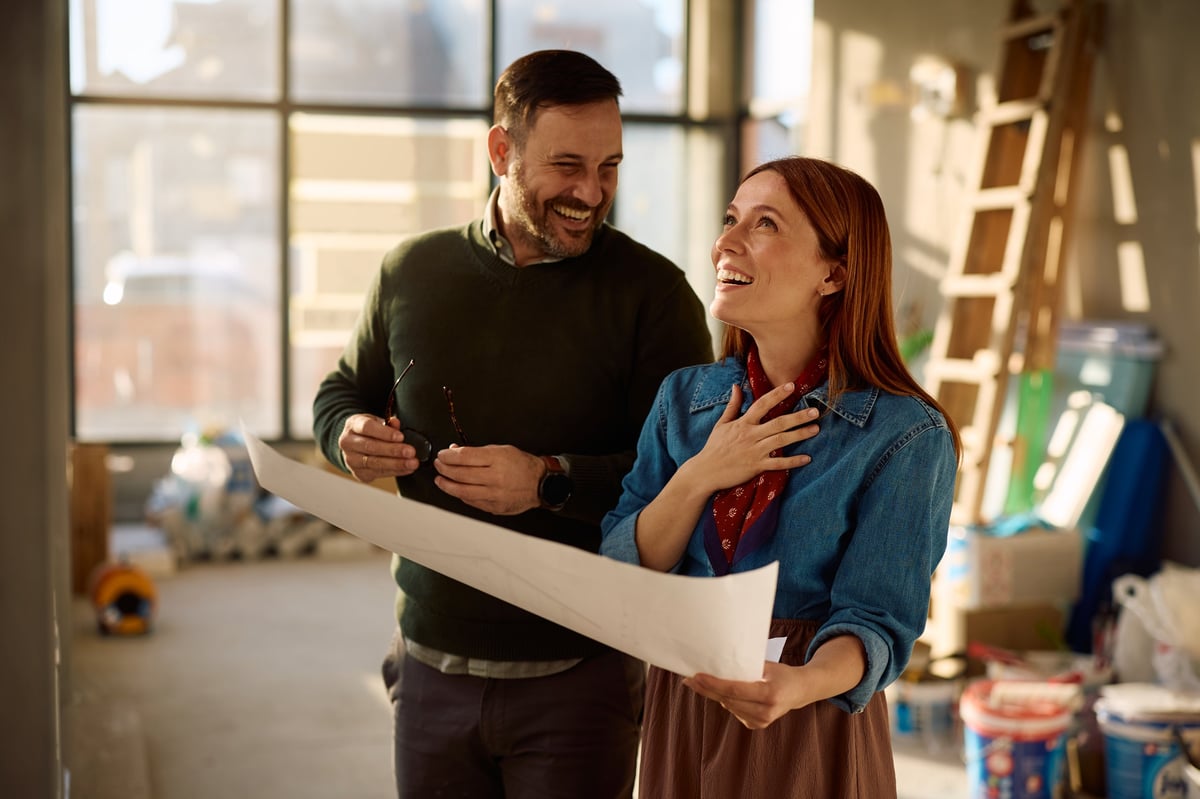Happy couple examining blueprints during home remodeling